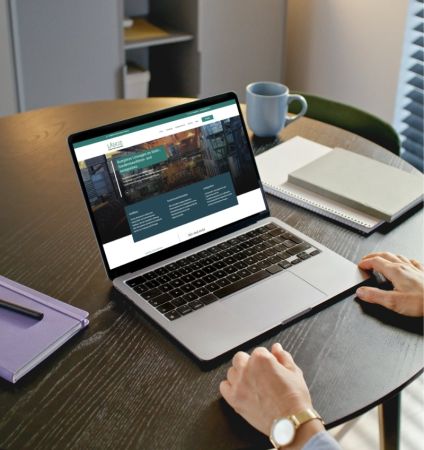 Auf dem Bild wird ein Bürotisch gezeigt auf dem ein Laptop steht. Auf dem Screen ist die Webseitenstartseite zu sehen. Webentwicklung gehört zu den Kompetenzen von BEPOINT Medien.